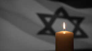Burning candle on Israel flag background. International Holocaust Remembrance Day, January 27.